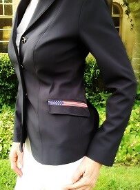 A woman wearing a black jacket with an american flag patch on the pocket.