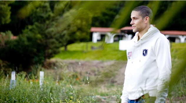 A man standing in the grass near some trees.