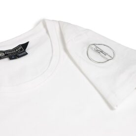 A white t-shirt with a metal emblem on the sleeve.